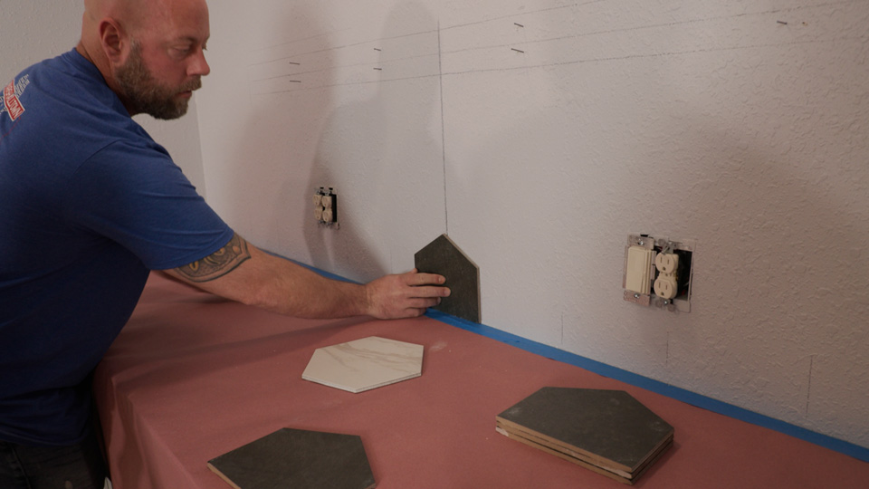man lining up the first tile in the center of the wall